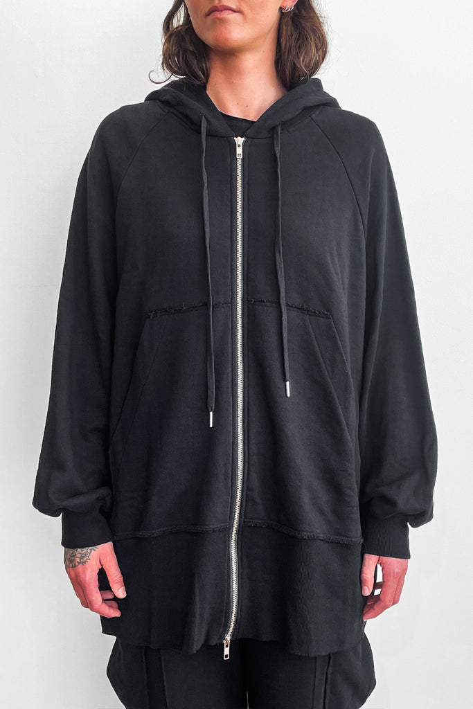 Close up of model wearing an long, oversized black zip-up hoodie with shorts