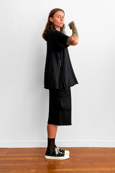 Side view of a model wearing an oversized black t-shirt and shorts. The t-shirt has a zip detail on the side