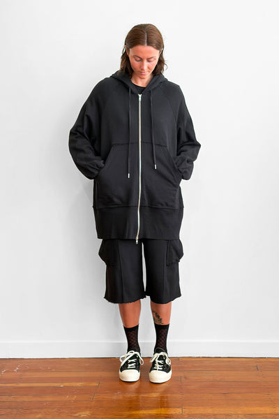 Model wearing an long, oversized black zip-up hoodie with shorts