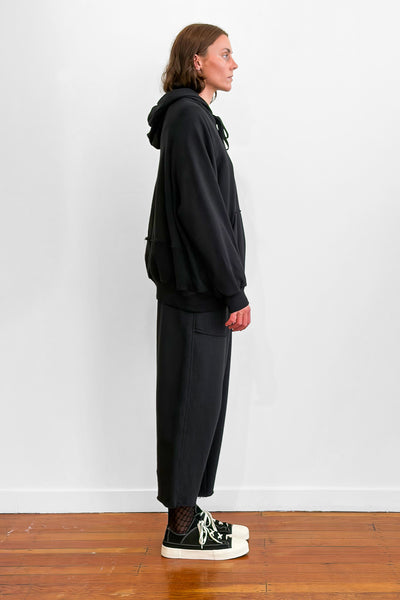 Side view of a model wearing an oversized black cotton hoodie with track-pants
