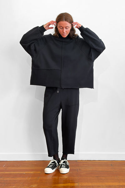 Model wearing an oversized black cotton sweater with track-pants