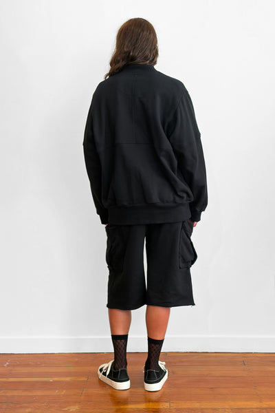 Back view of a model wearing an oversized black zip sweater and shorts