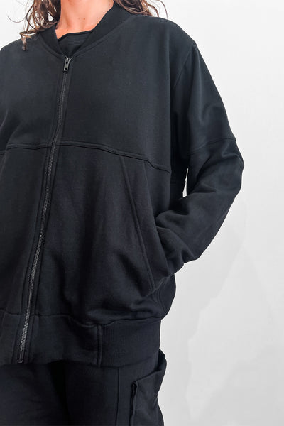 Close up of a model wearing an oversized black zip sweater and shorts