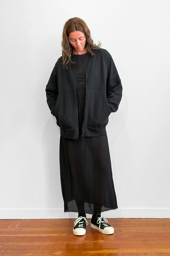 Model wearing an oversized black zip sweater over a long black dress