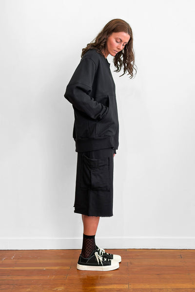 Side view of a model wearing an oversized black zip sweater and shorts